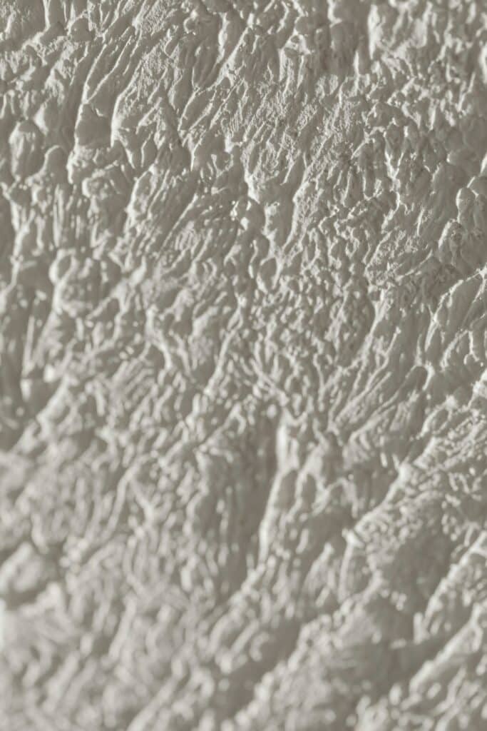 A close up image of white spray foam expanding and filling gaps. The foam has a bubbly texture and appears freshly applied.